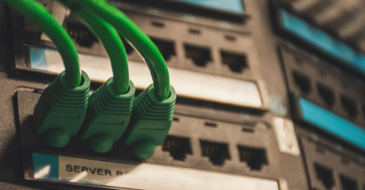 Close-up of green network cables plugged into server ports showcasing technology setup