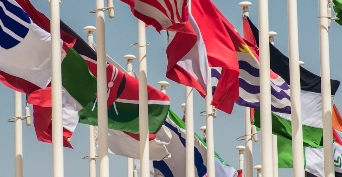 Colorful international flags waving on flagpoles against a clear blue sky symbolizing unity and diversity