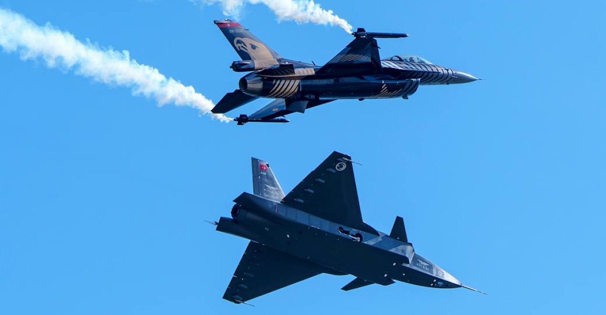 Two military aircraft performing a synchronized flyover with vapor trails against a clear blue sky