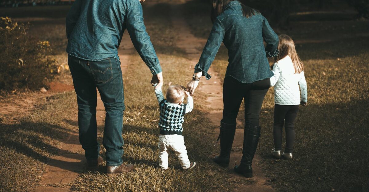 A family of four walks hand in hand on a path enjoying a sunny day outdoors