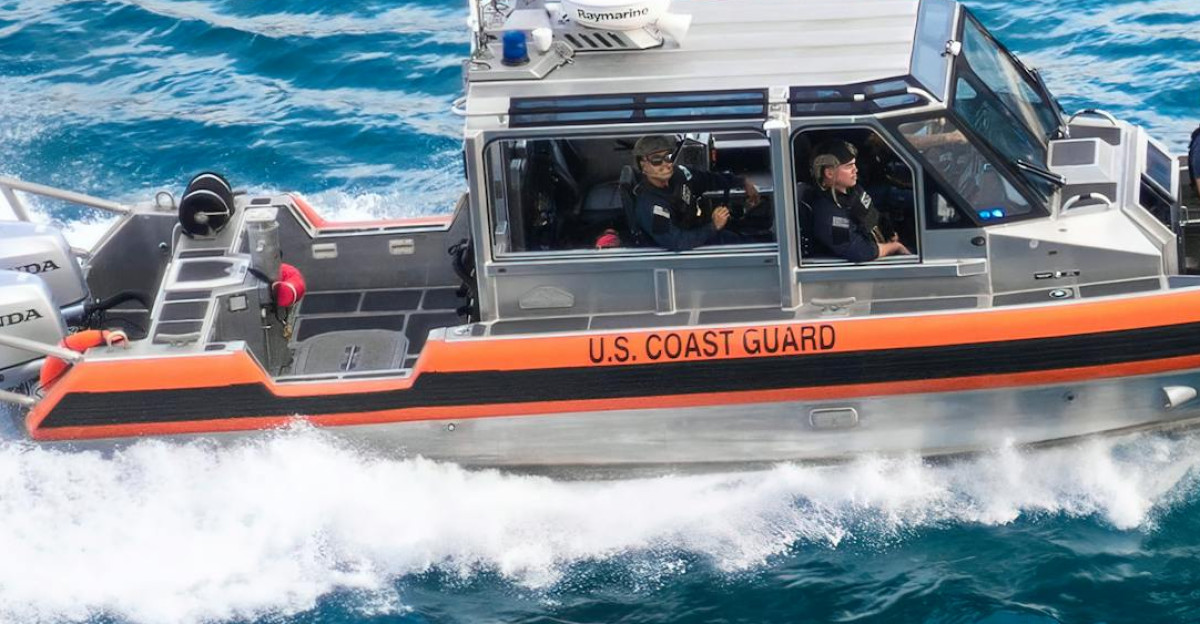 Dynamic U S Coast Guard patrol boat speeding through blue ocean waters showcasing security and marine operations