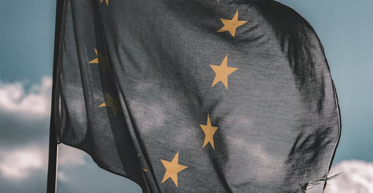European Union flag gently waving on a flagpole against a cloudy sky symbolizing unity and patriotism