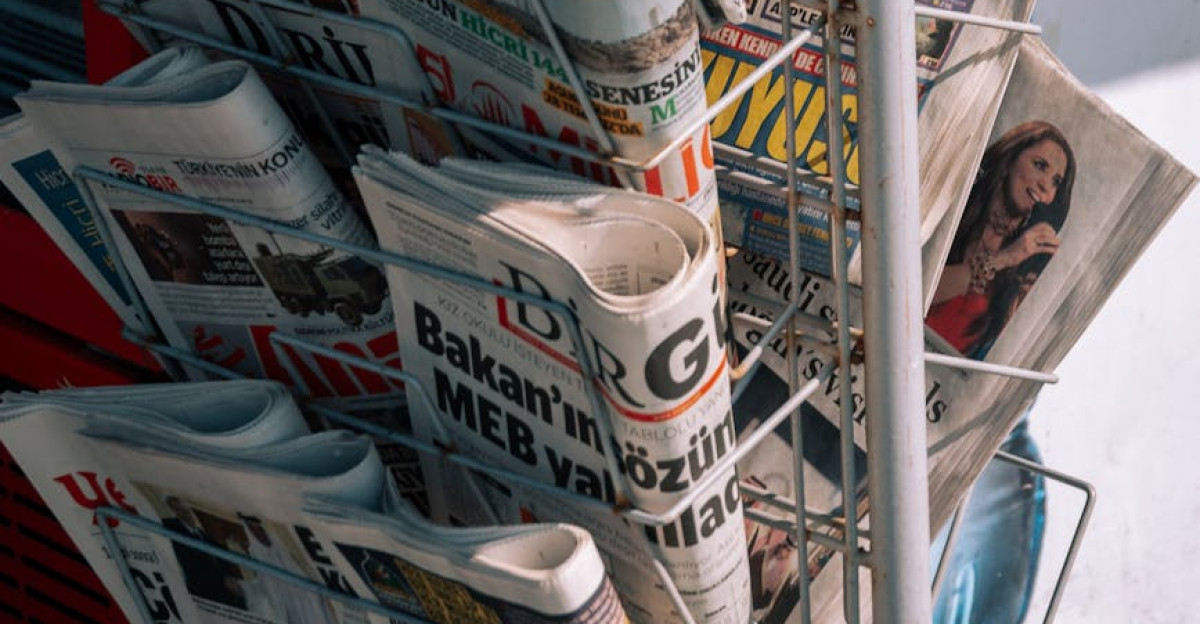 Close-up of a newspaper stand with various publications on a city sidewalk