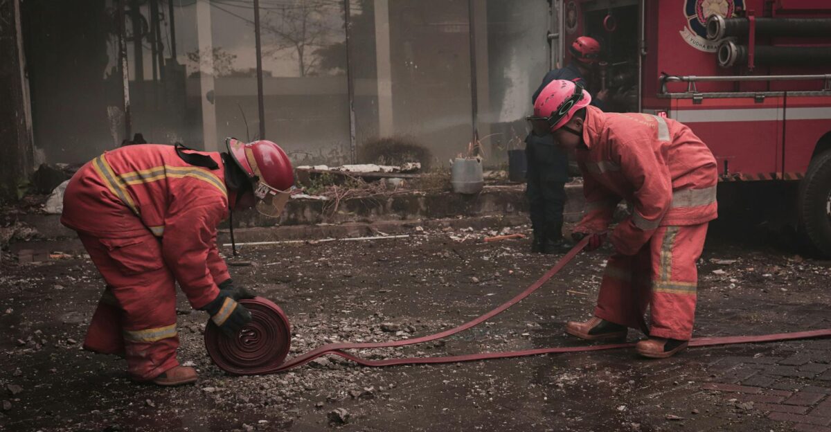 Firefighters manage hoses during a city street operation in Makassar Indonesia