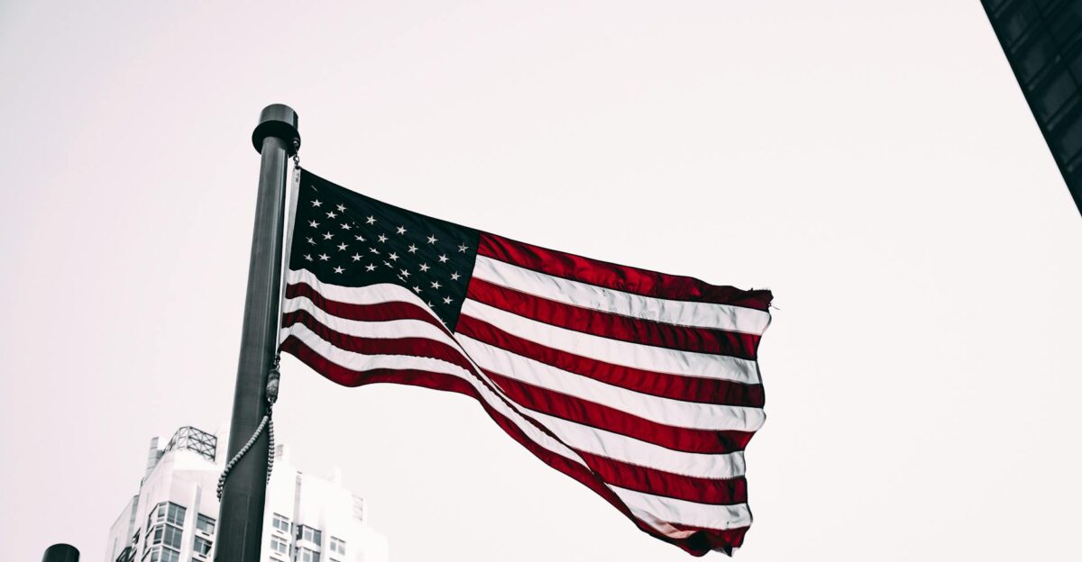 Patriotic image of the American flag waving in the wind with city skyscrapers in the background