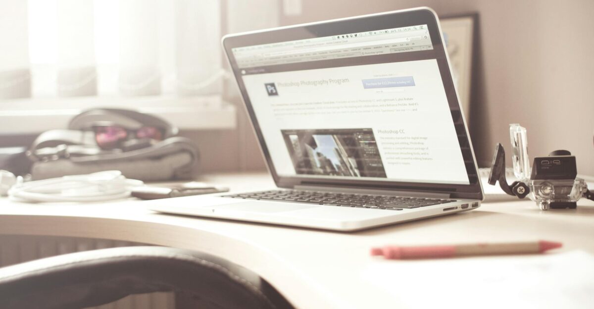 A clean and bright workspace featuring a laptop open on a wooden desk highlighting a typical tech environment
