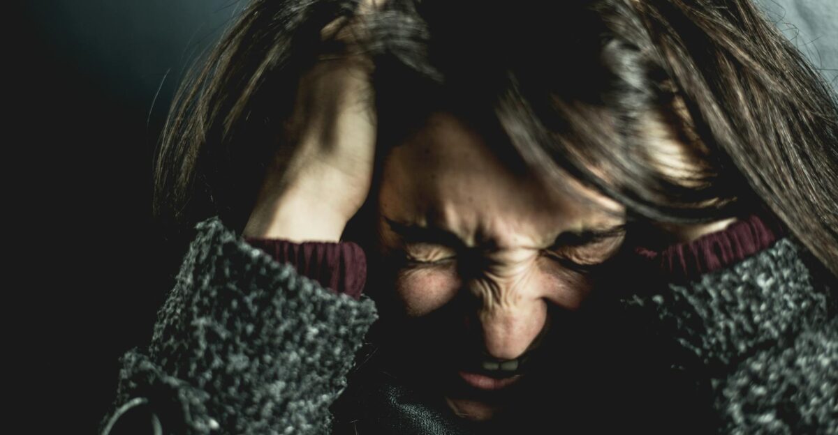Close-up of a woman in distress with eyes closed and hands in hair expressing anxiety