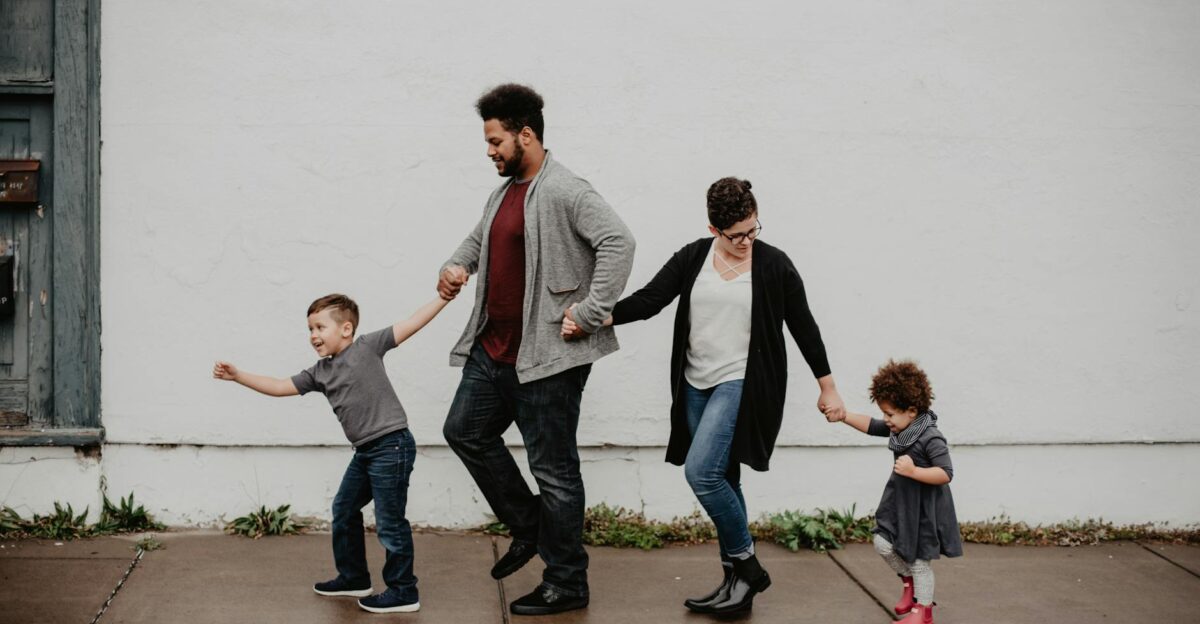 A joyful family walking together outdoors holding hands in a playful and happy moment