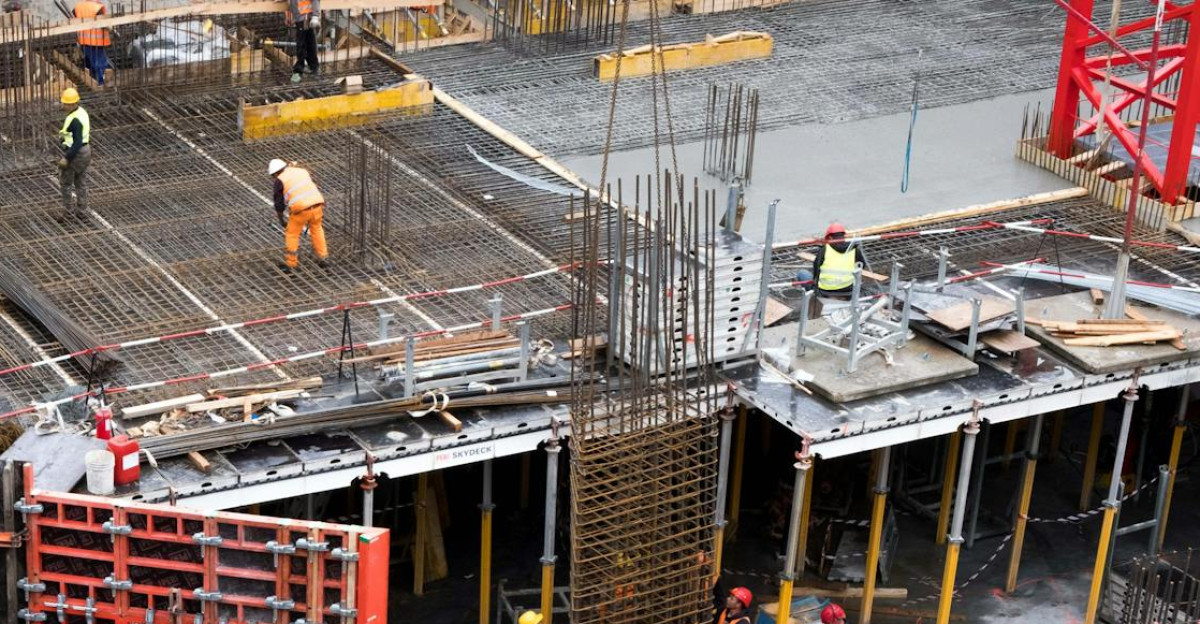 Industrial construction site with workers in high visibility clothing at a steel framework structure