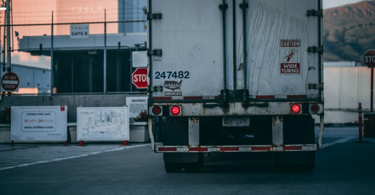 Semi truck parked at a loading dock with visible caution signs and industrial surroundings