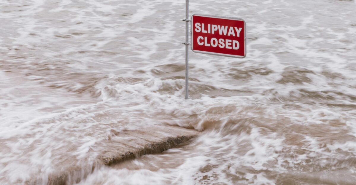 Flooded slipway with red Slipway Closed sign surrounded by flowing waves