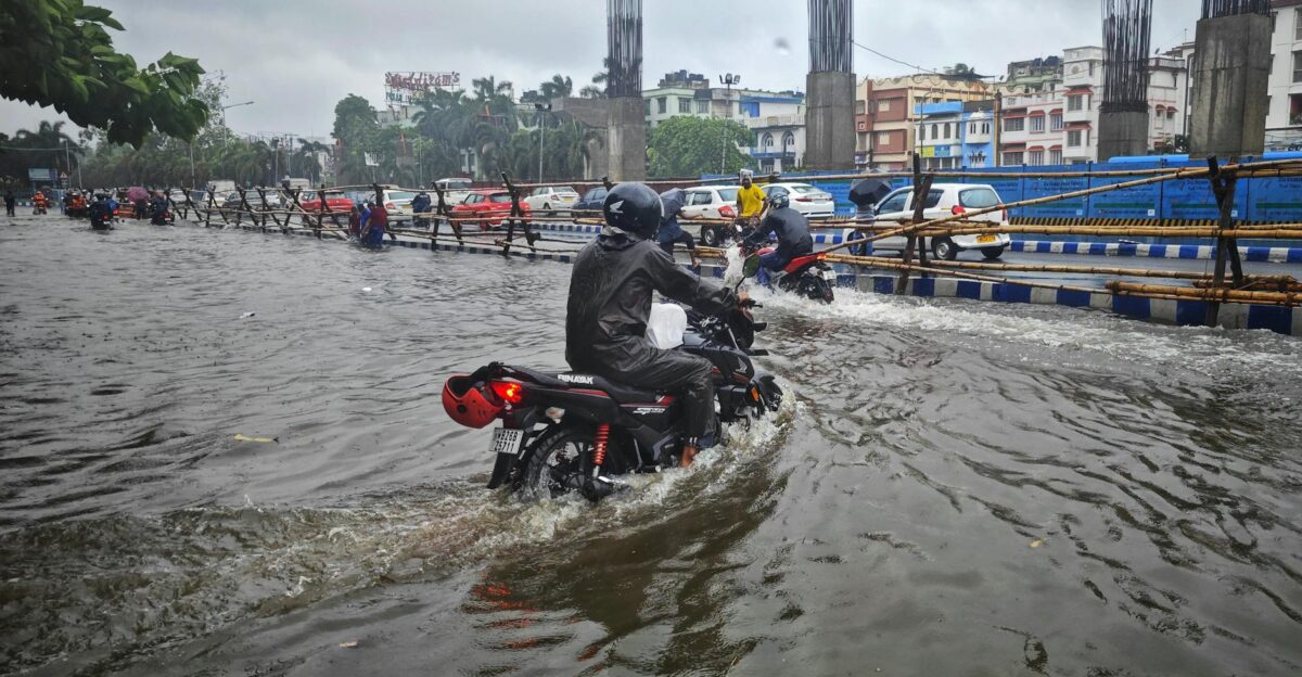 Motorcyclists navigating a flooded street in Kolkata India during a heavy rain