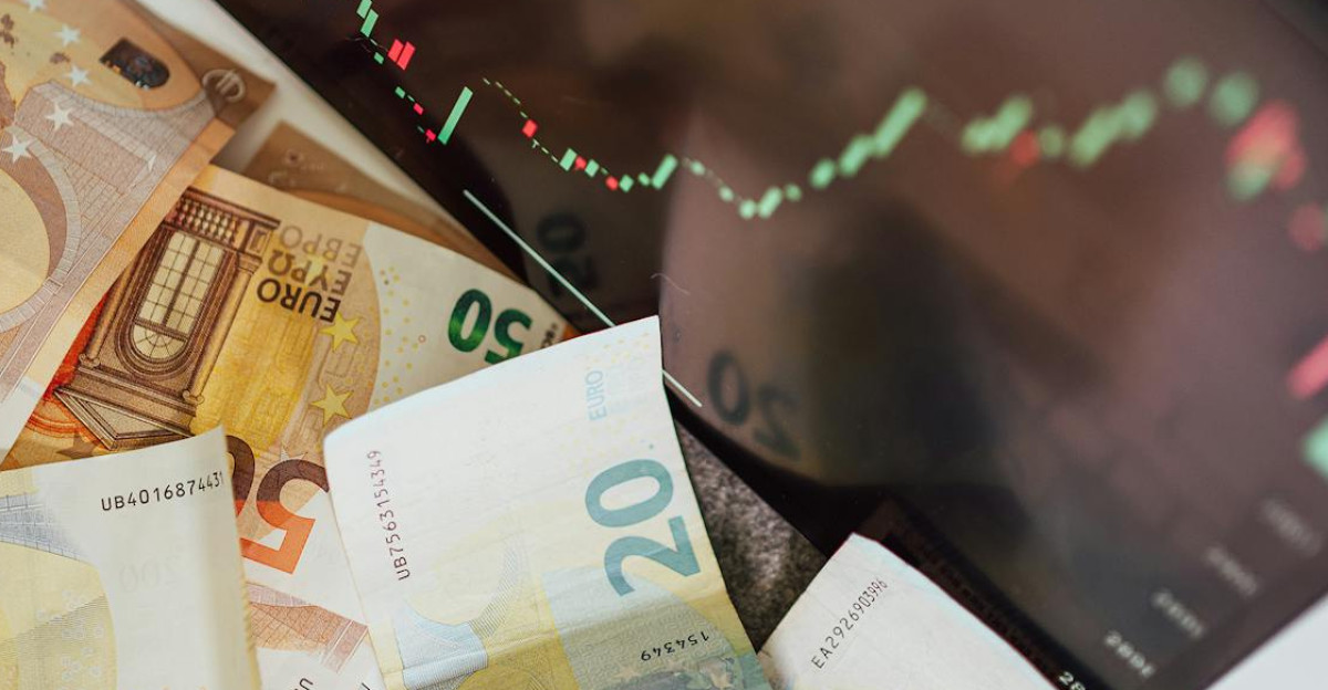 Close-up of euro banknotes with a digital stock market chart displaying a downward trend symbolizing financial volatility