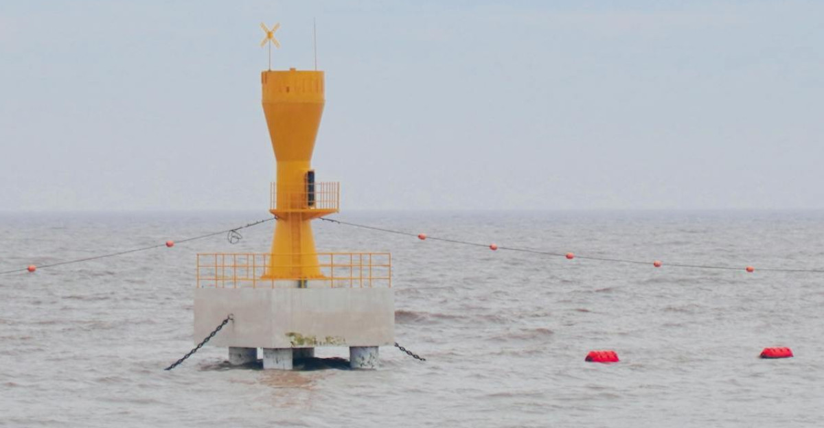 Yellow buoy marking navigation point in the vast tranquil sea under a clear blue sky