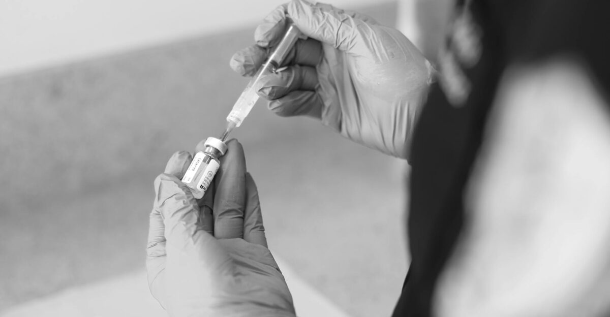 A healthcare worker prepares a syringe with medication in a clinical setting