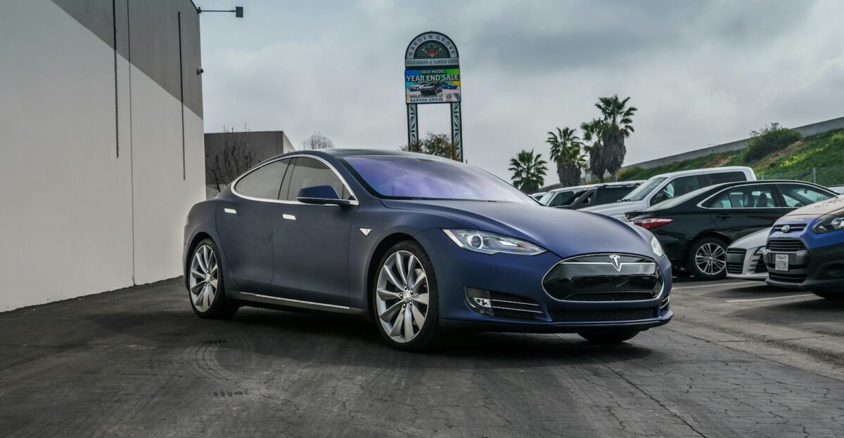 A sleek navy blue Tesla Model S electric vehicle parked in an urban setting