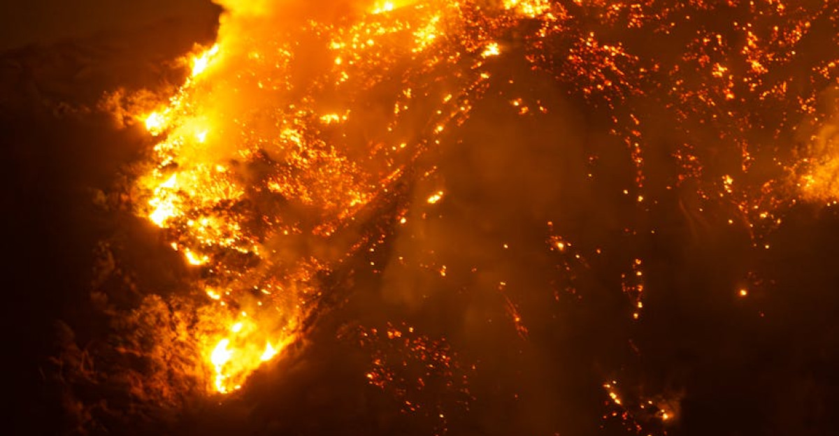 Dramatic view of a wildfire burning fiercely on a hillside at night in California