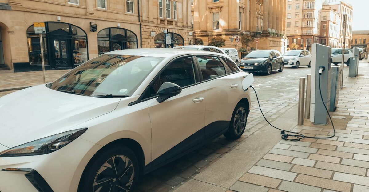 White electric car charging at a modern station on a Glasgow street