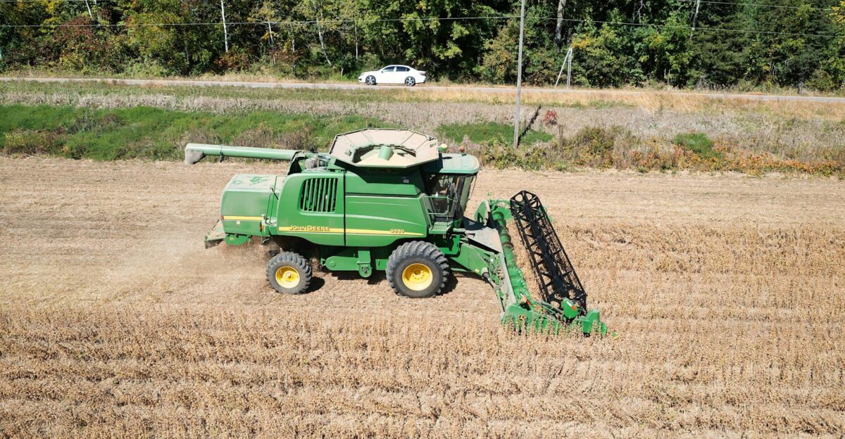 Aerial view of combine harvester in field with forest background in Minnesota