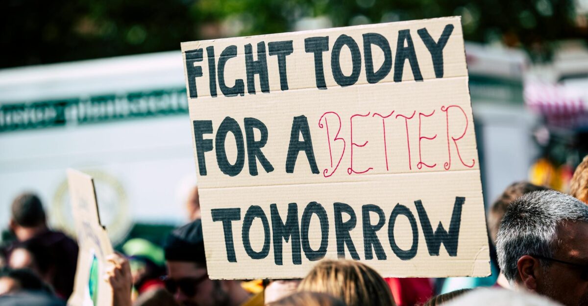 Crowd holding a protest sign with Fight Today for a Better Tomorrow outdoors and during the day