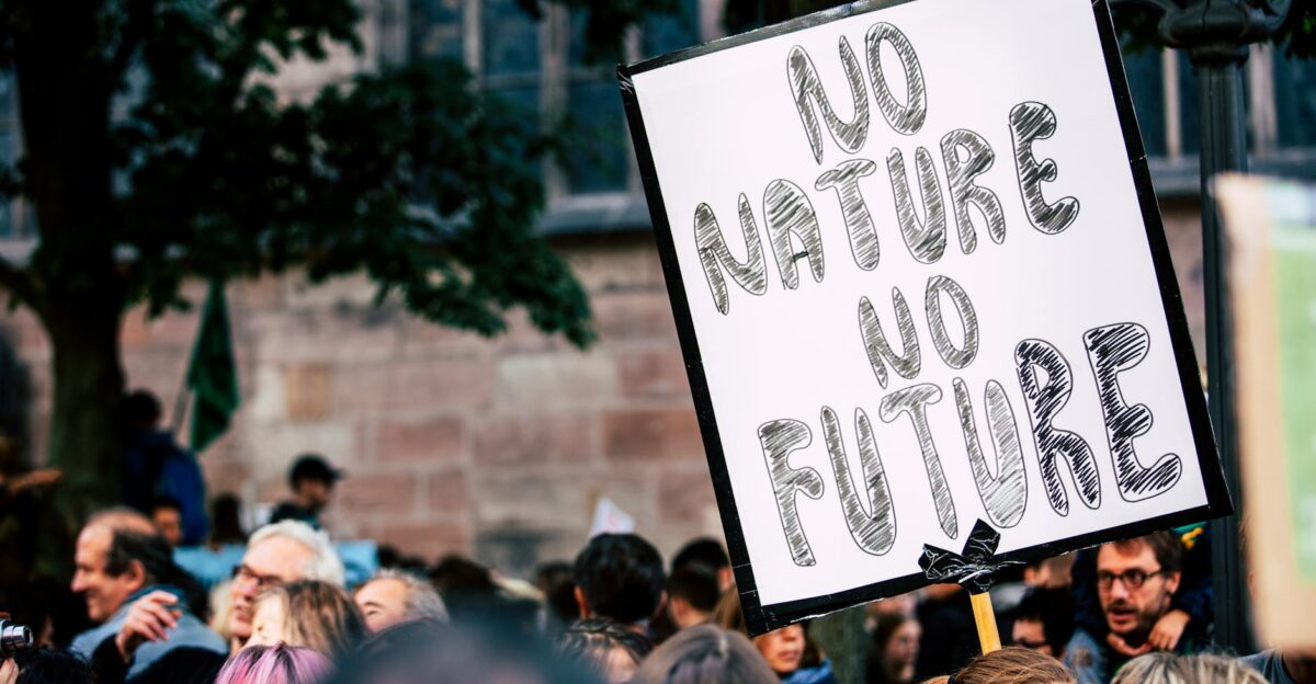 Large group of people rallying with a sign advocating for nature protection and climate action