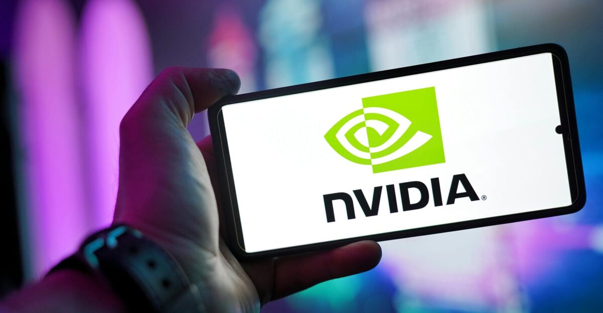 Close-up of a hand holding a smartphone showing the NVIDIA logo on screen with a blurred background