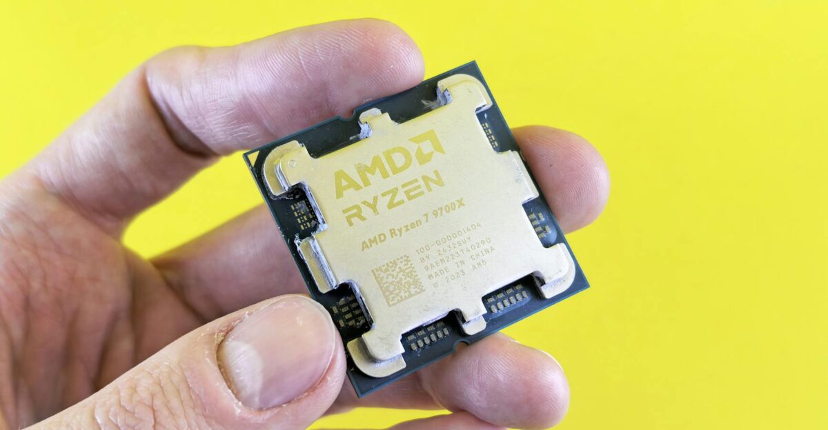 Detailed shot of AMD Ryzen 7 9700X processor held against bright yellow background