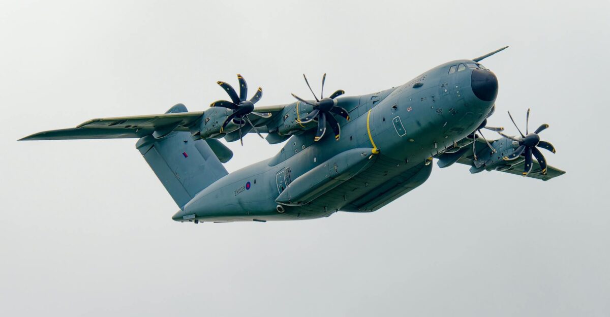 Dynamic shot of a military A400M aircraft flying against a grey cloudy sky background