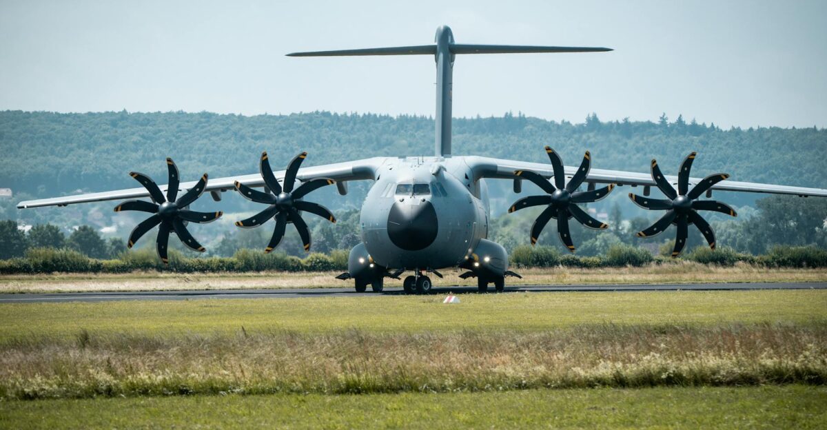 Front view of a military A400M aircraft on the runway against a forest backdrop