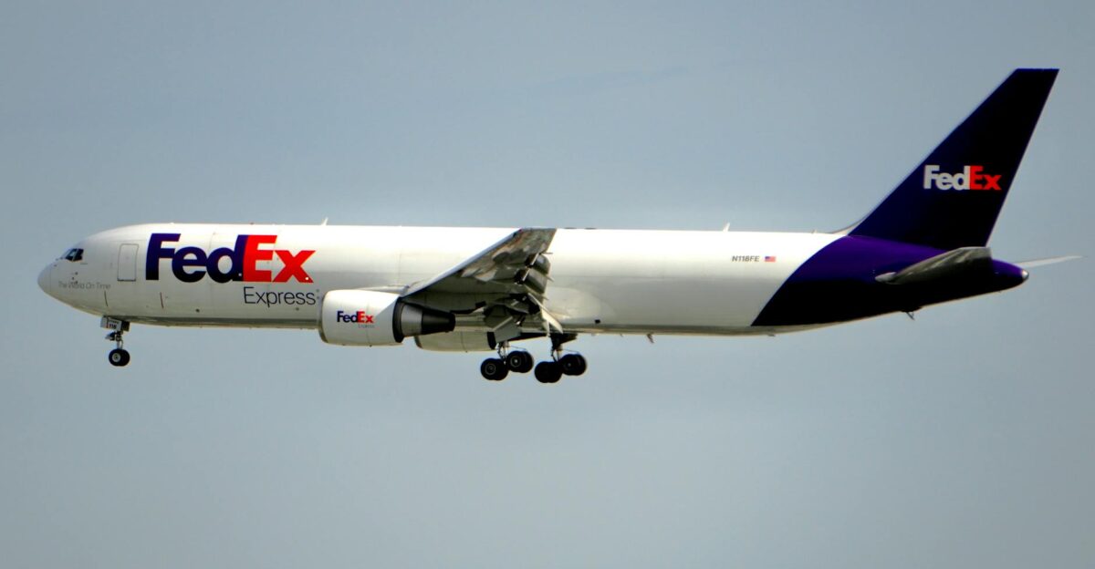 A FedEx cargo plane captured in mid-flight against a clear blue sky showcasing air logistics