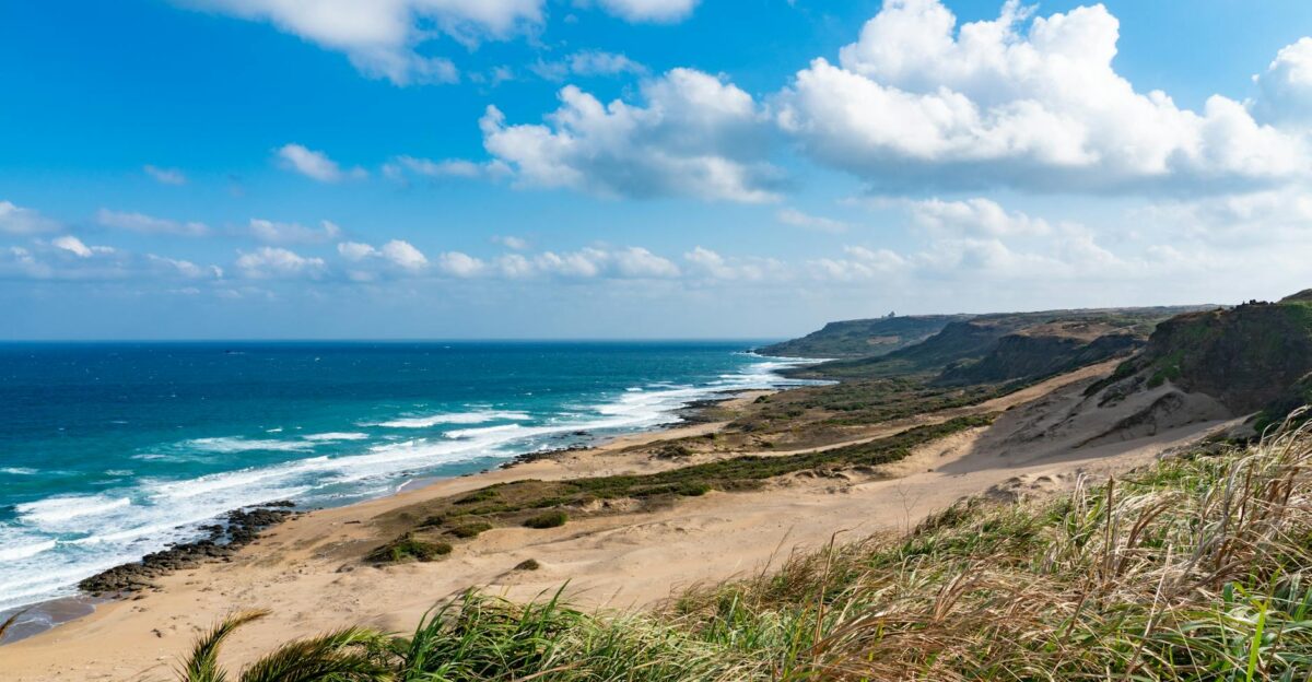 Amazing view of sandy seashore near foamy blue sea beneath clear blue sky