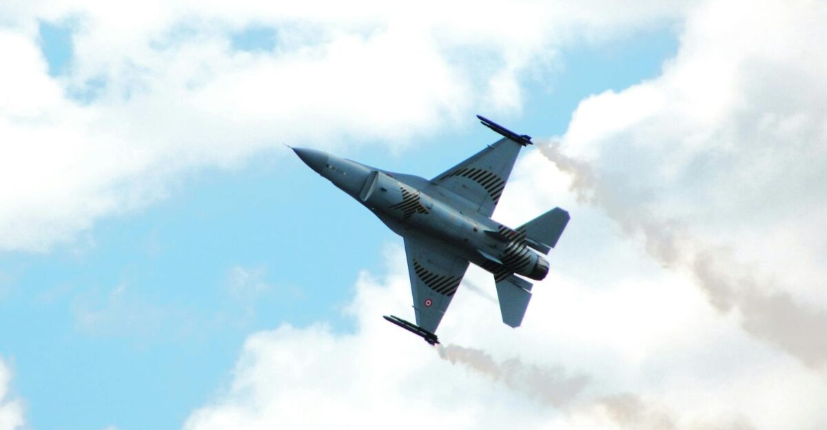 Fighter jet executing an aerobatic maneuver against a cloudy sky backdrop