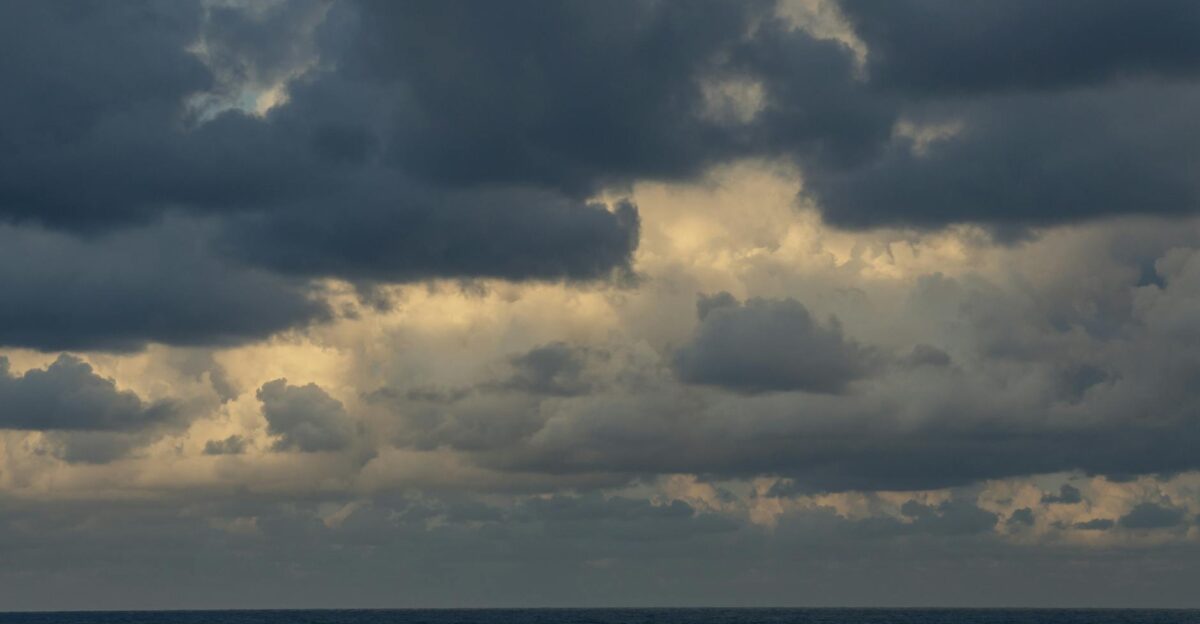 Stormy clouds gather over the ocean as daylight fades into evening