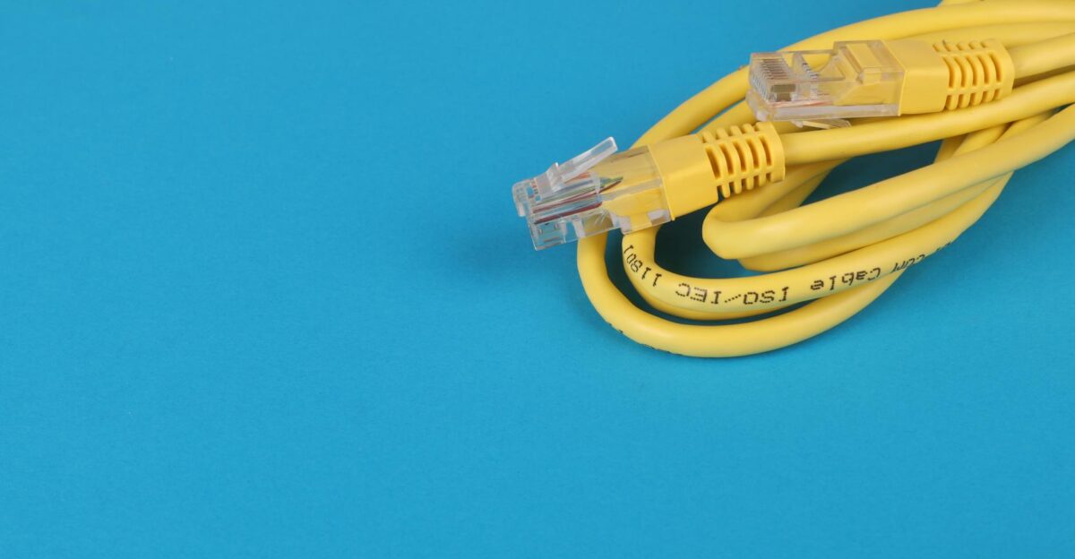 Close-up of a yellow Ethernet cable with connectors on a blue background