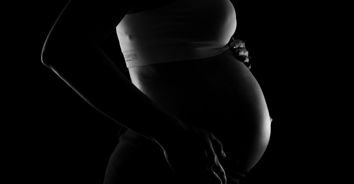 Captivating grayscale close-up of a pregnant woman highlighting a baby bump conveying anticipation and love
