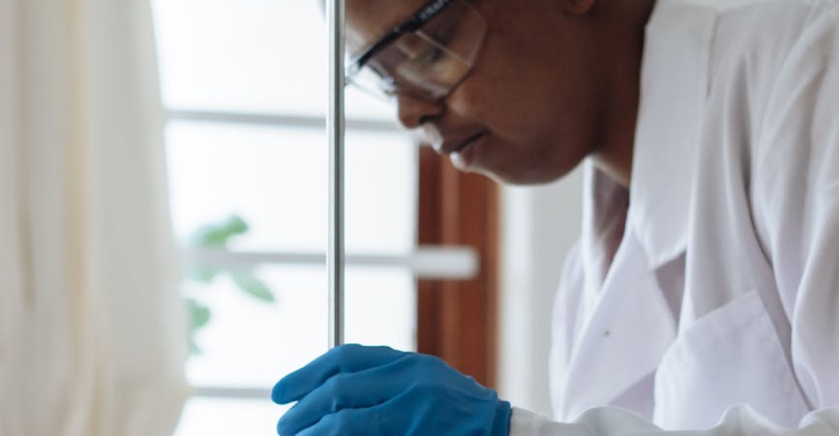 Professional scientist wearing a lab coat and gloves conducting an experiment with glassware indoors