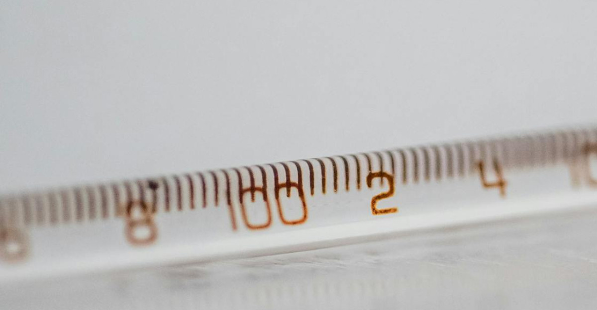 Detailed close-up of a mercury glass thermometer on a white surface showing temperature measurements