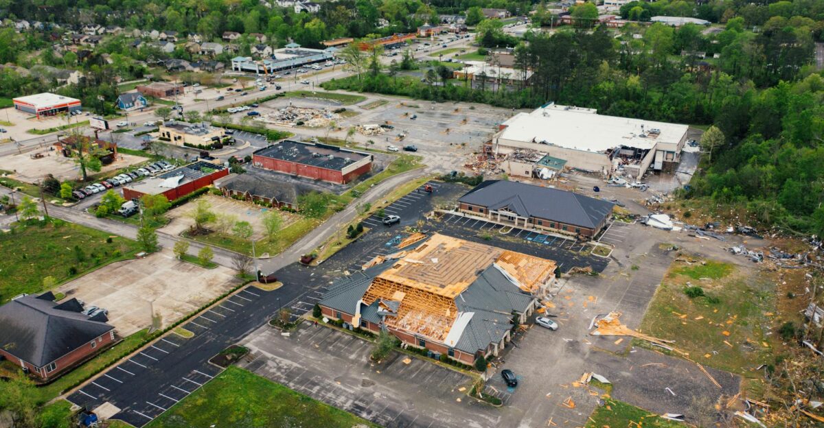 Aerial view of terrible consequences of thunderstorm on small town buildings with ruined roof and uprooted trees
