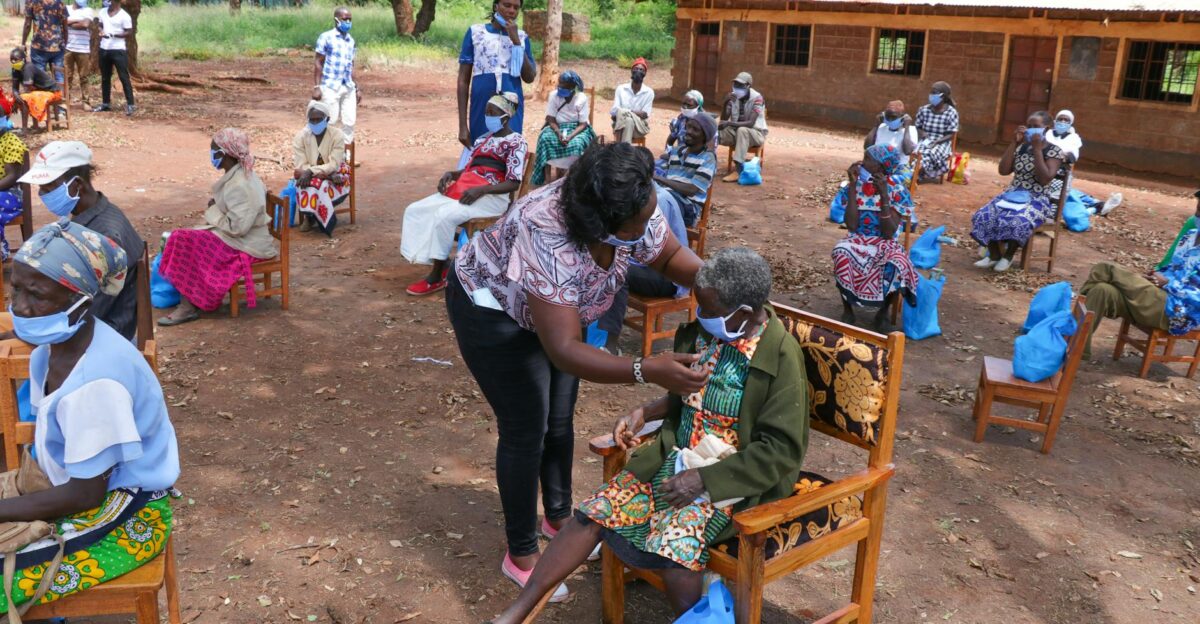 Aid workers assist elderly people with healthcare support in a rural setting