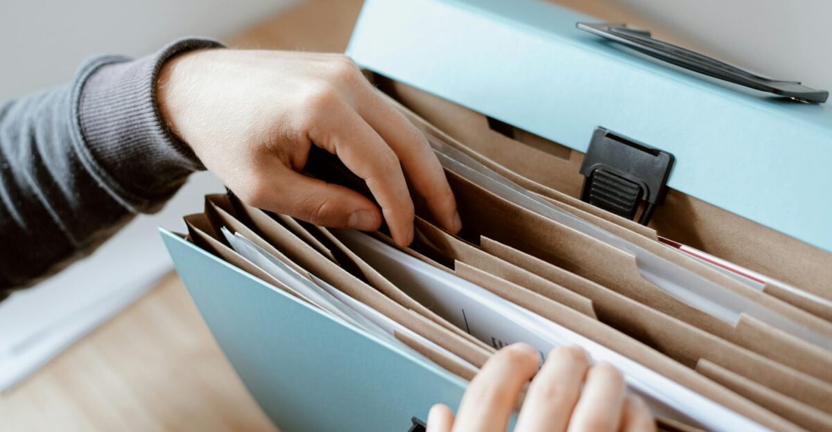 Close-up of hands organizing papers in a blue folder ideal for business and office concepts