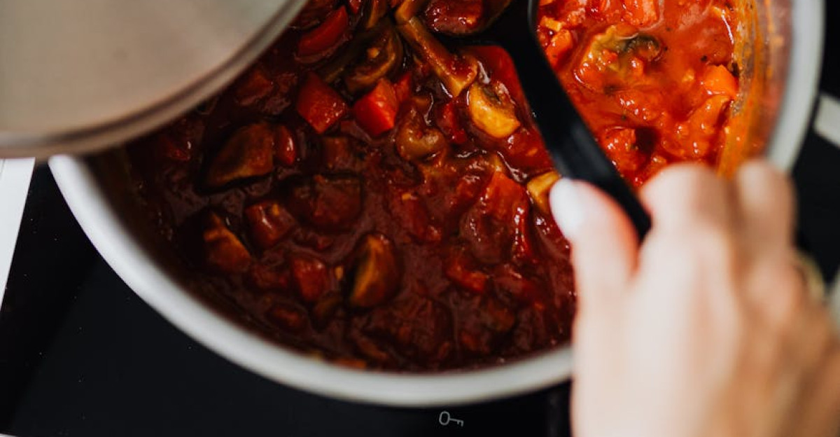 Close-up of shakshuka cooking in pot with spoon stirring Perfect for culinary enthusiasts