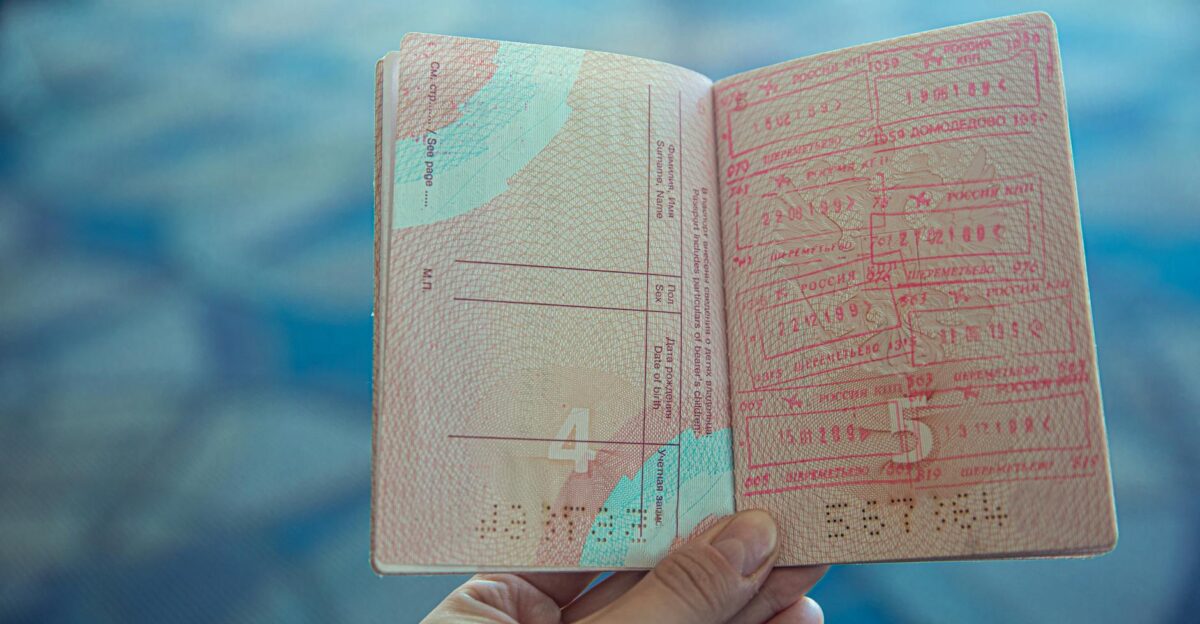 Close-up view of an open passport displaying various travel stamps in an airport setting