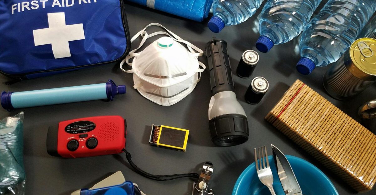 Flat lay of essential emergency survival kit items including first aid and water bottles