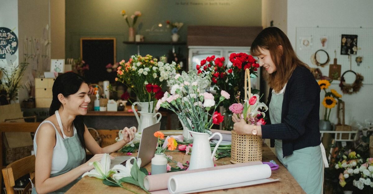 Two women florists happily arranging flowers in a cozy flower shop workspace