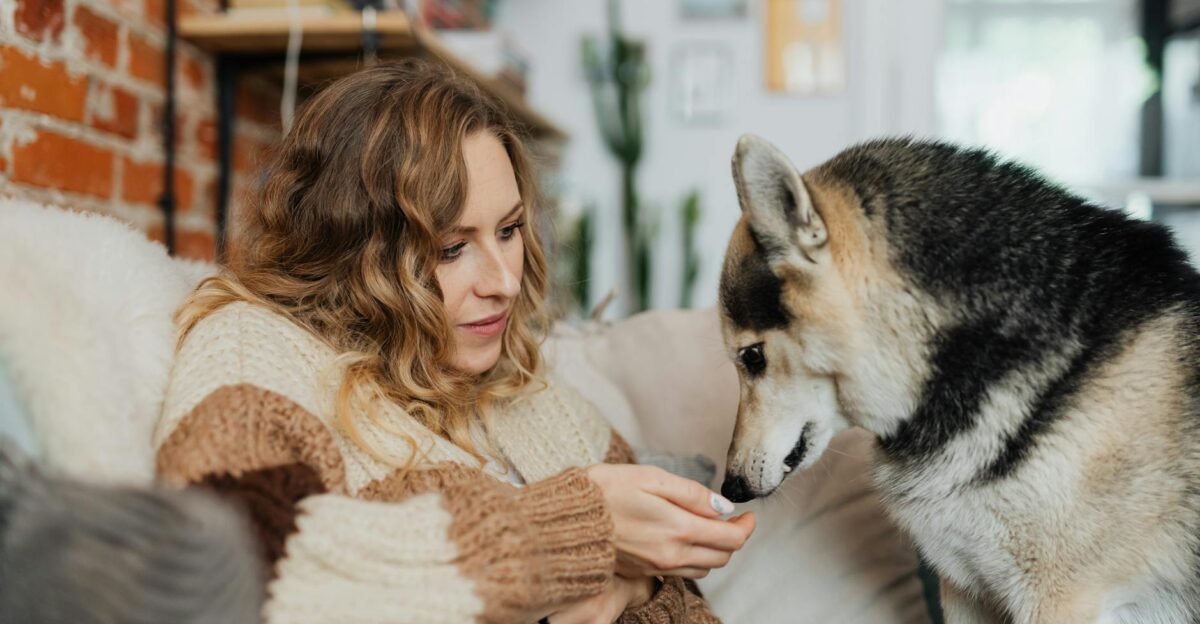 Woman relaxing on couch with a Siberian Husky creating a cozy and warm atmosphere