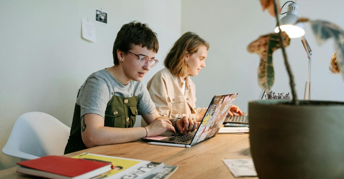 Two young professionals working collaboratively on laptops in a modern and creative workspace