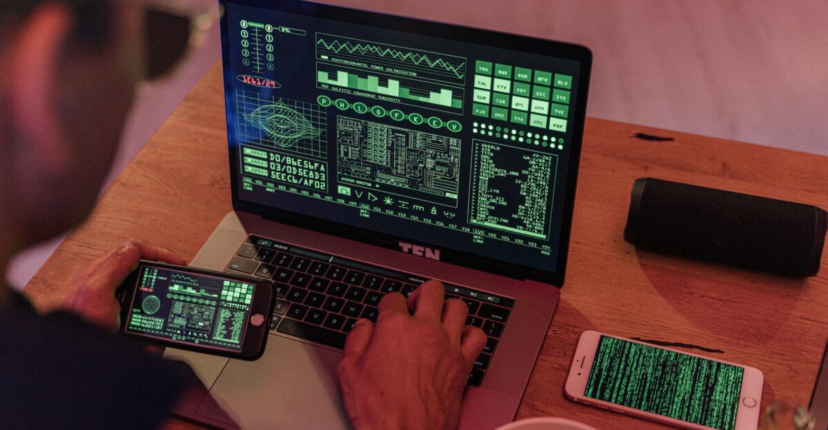 Man working with cybersecurity software on laptop and smartphone