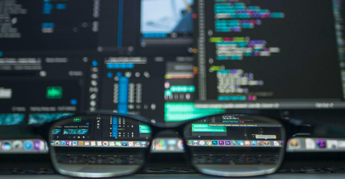 Eyeglasses reflecting computer code on a monitor, ideal for technology and programming themes.