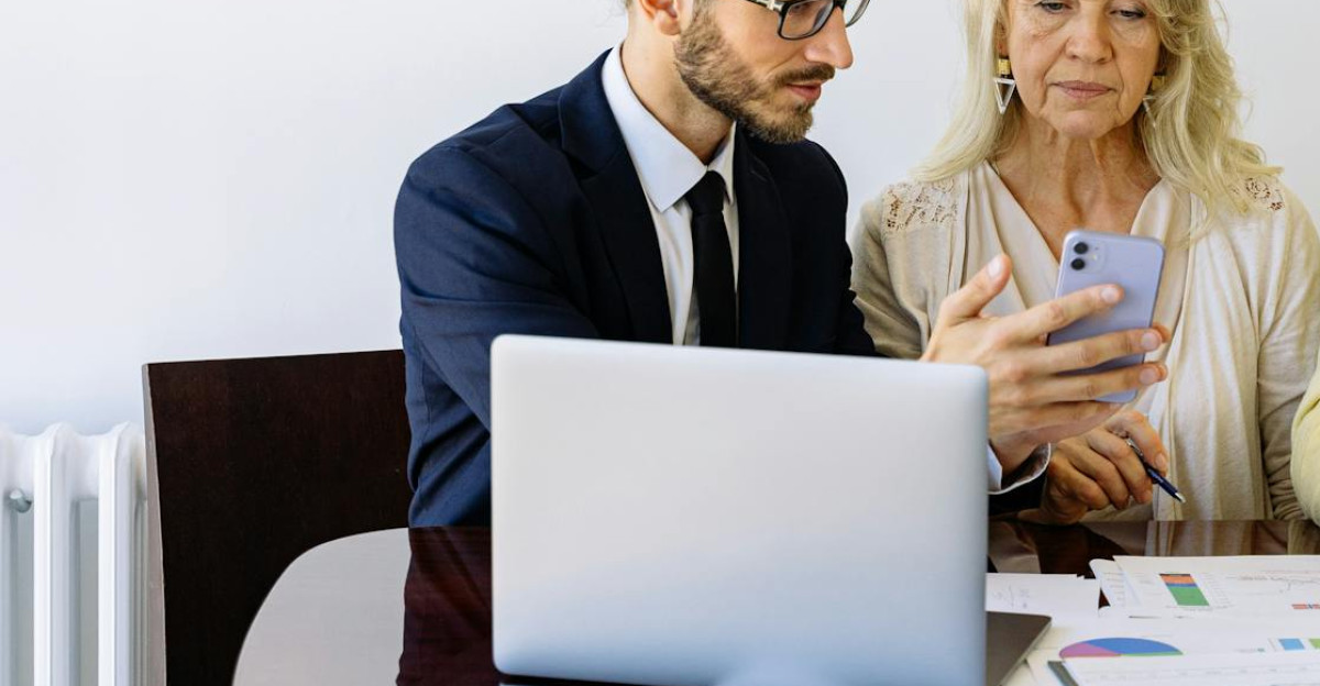Three individuals collaborating on financial documents during a business meeting