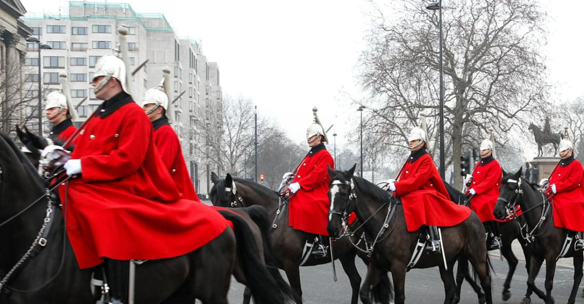 Horse Guards in red uniforms riding through London during a ceremonial parade